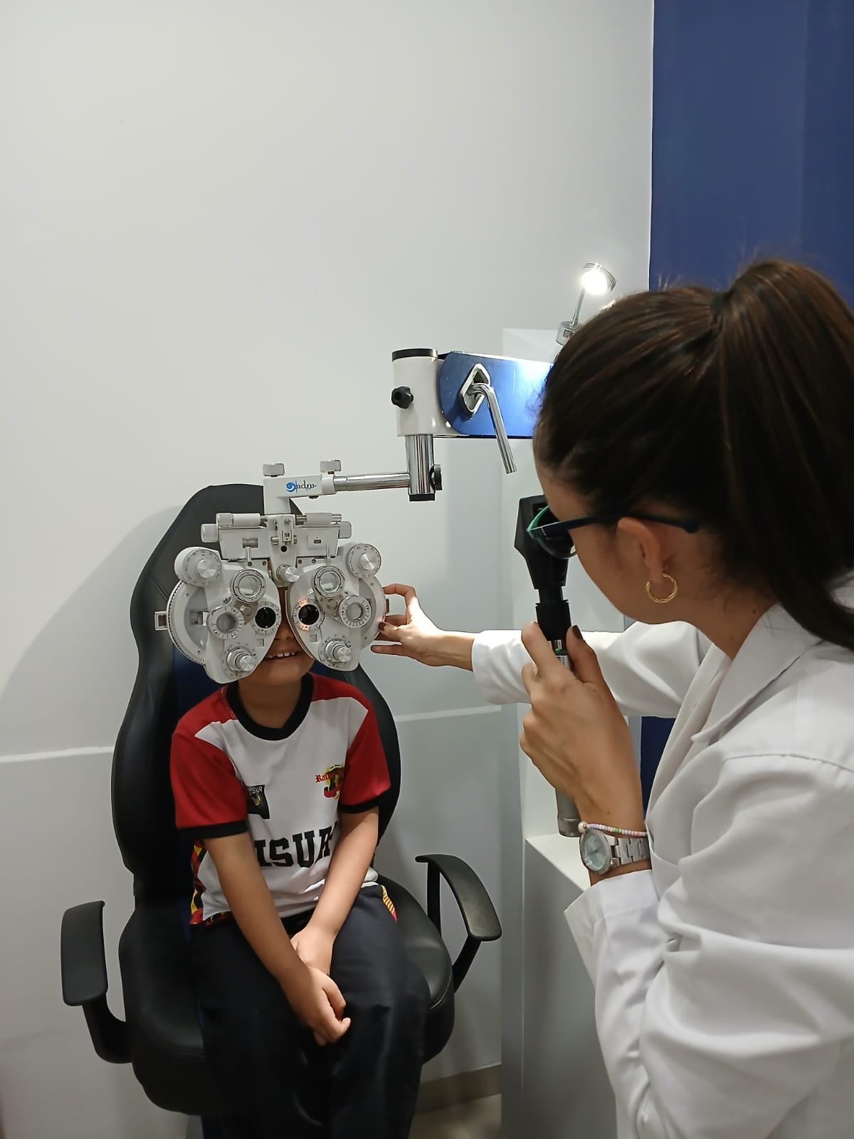 Optómetra de Óptica Infinito realizando un examen visual a un paciente joven con foróptero.